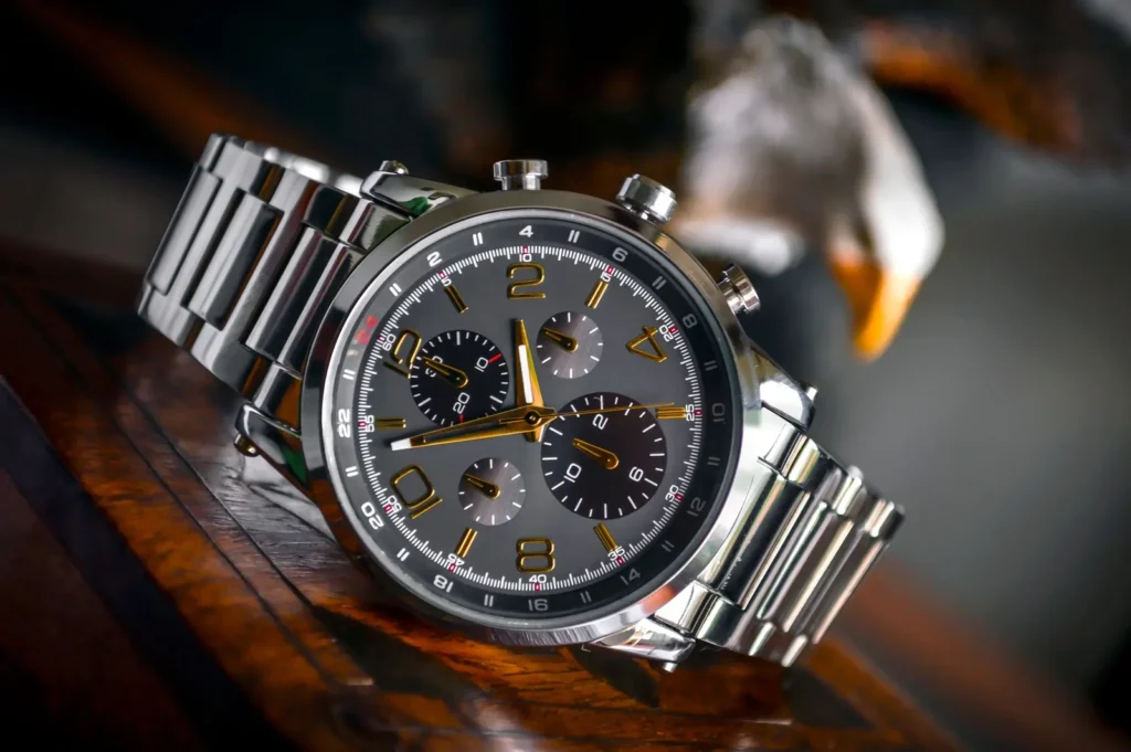 A plain steel wristwatch with a white dial lying on a rough grey concrete surface