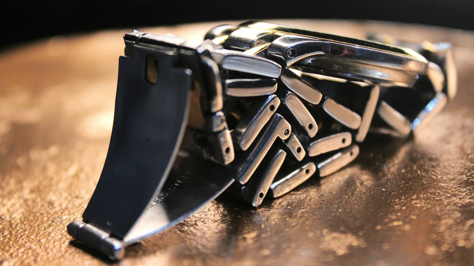 A scratched and worn metal watch clasp showing the plating rubbed through at the edges