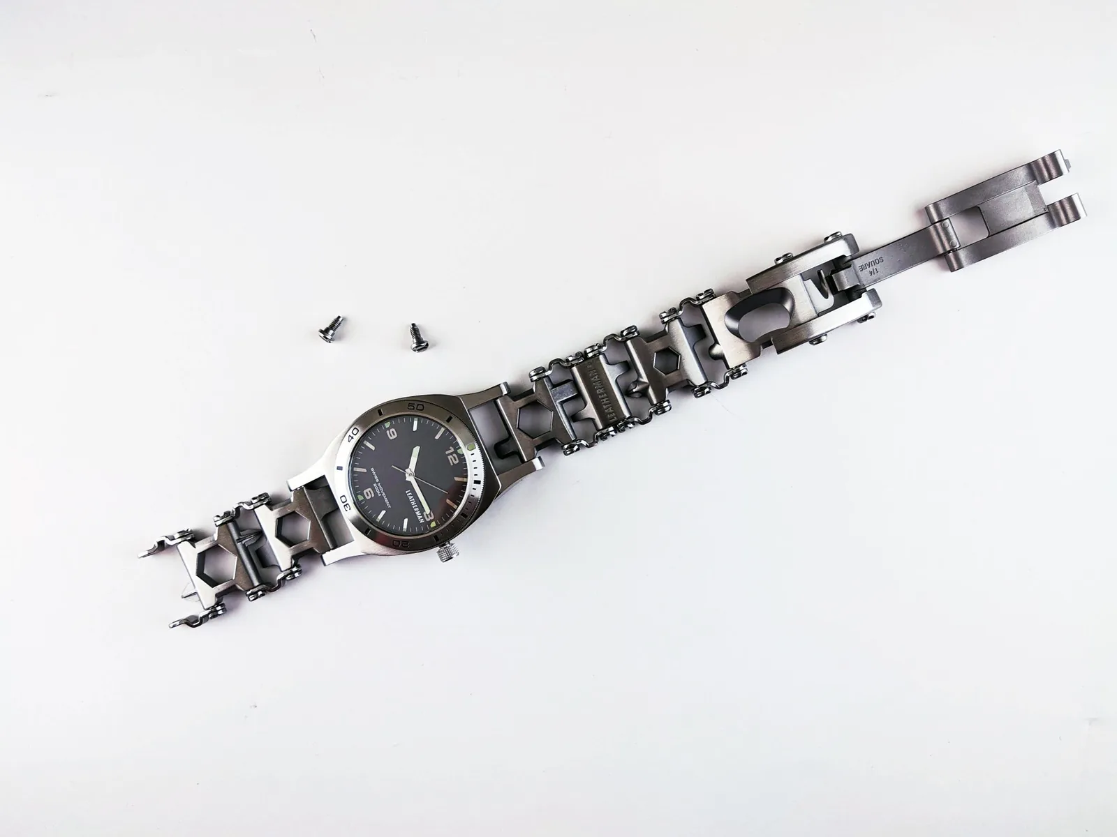Bracelet links and a sizing pin laid out beside a small tool