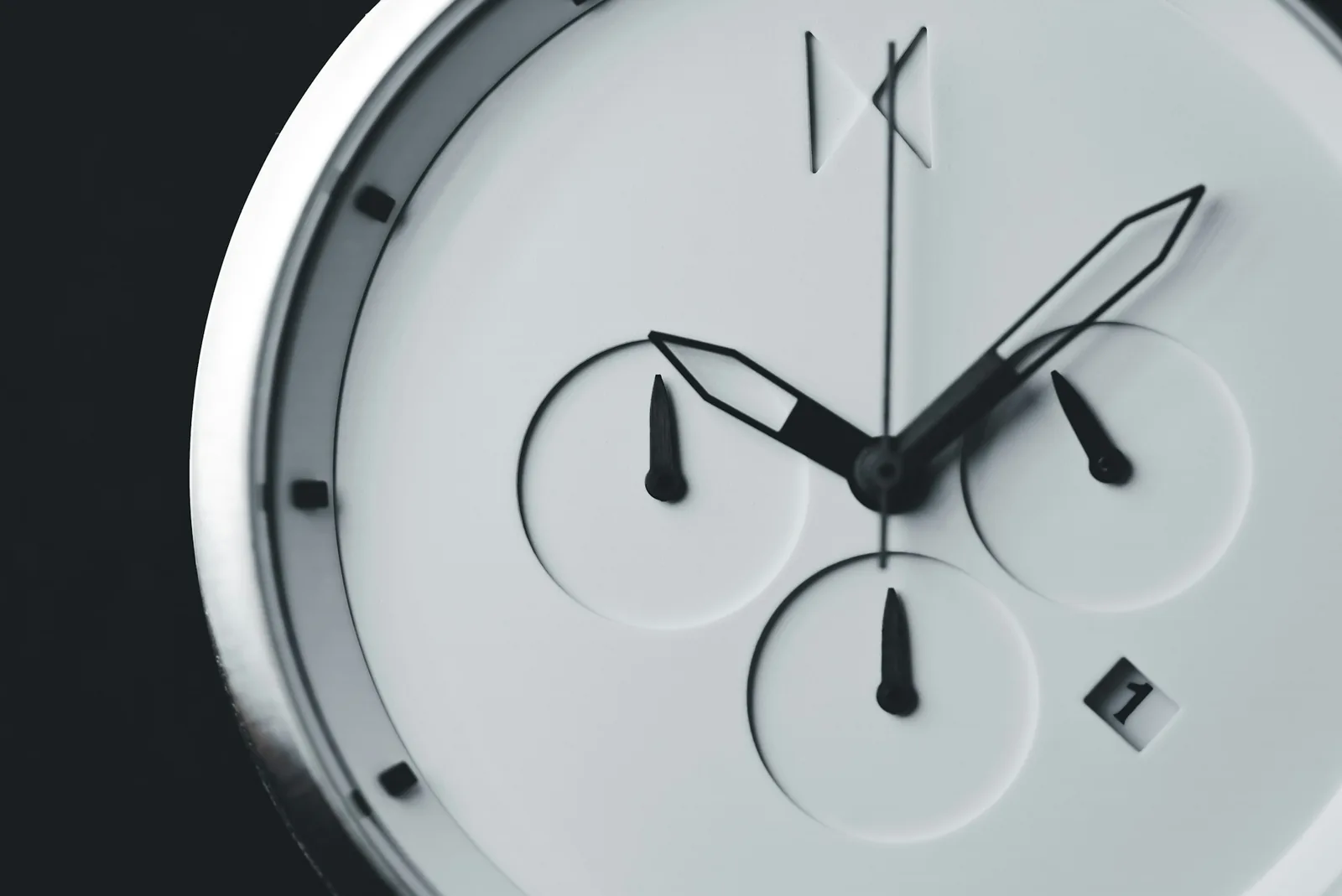 A plain white watch dial with slim markers photographed close up