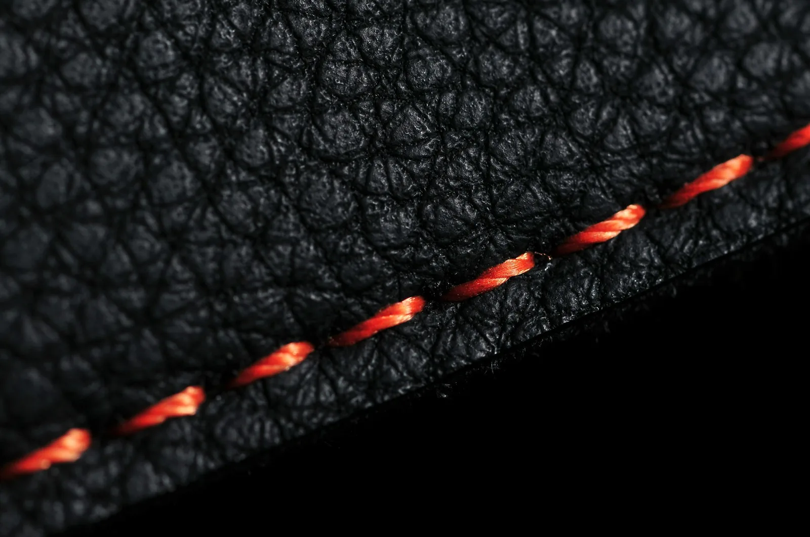 The stitching and grain of black leather seen close up