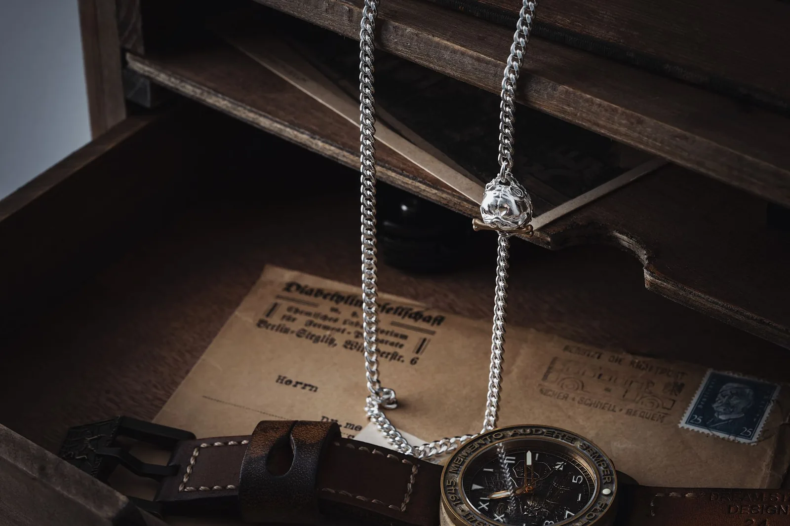 A wristwatch resting in a drawer beside a chain
