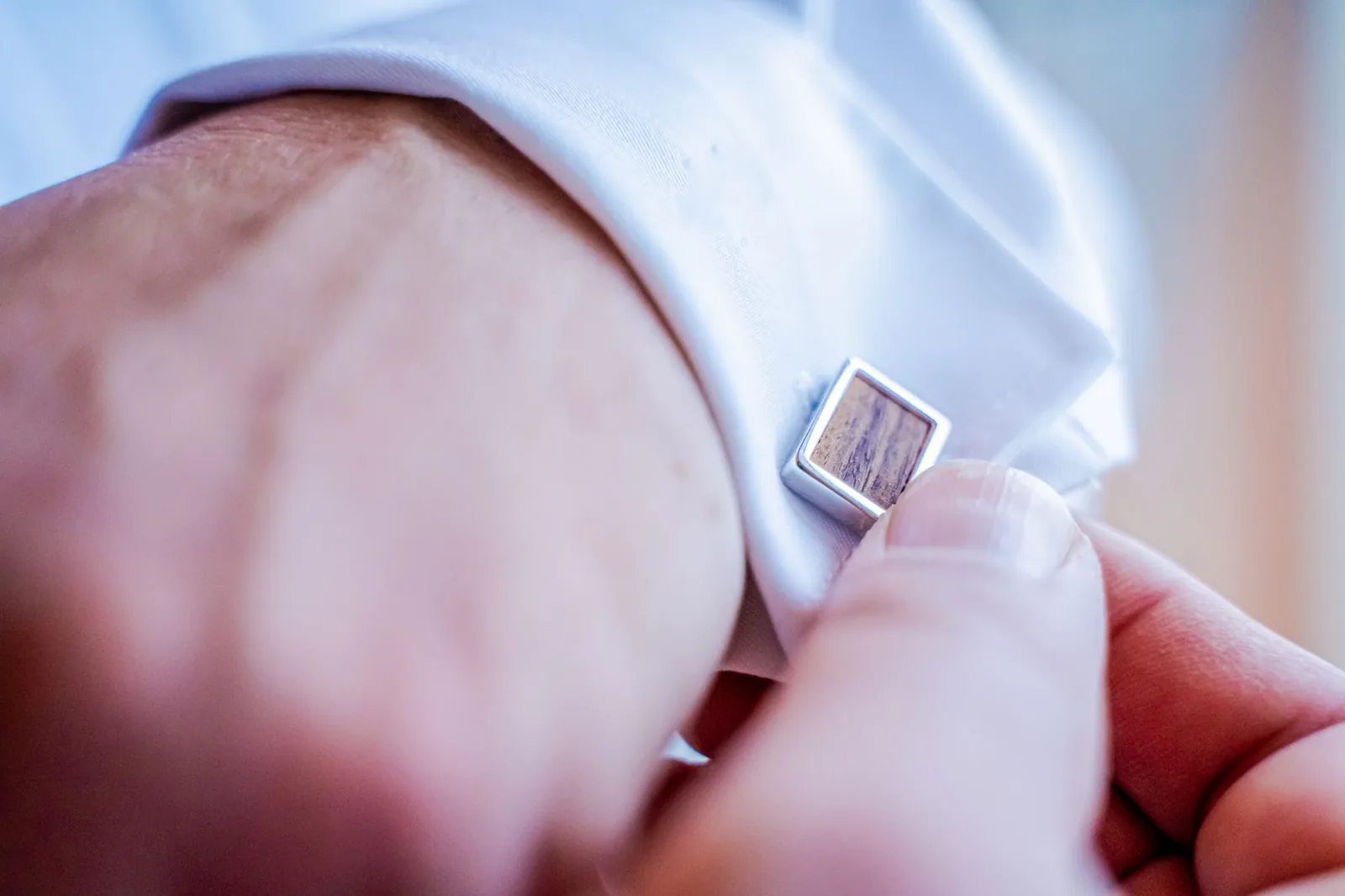 A shirt cuff being fastened at the wrist