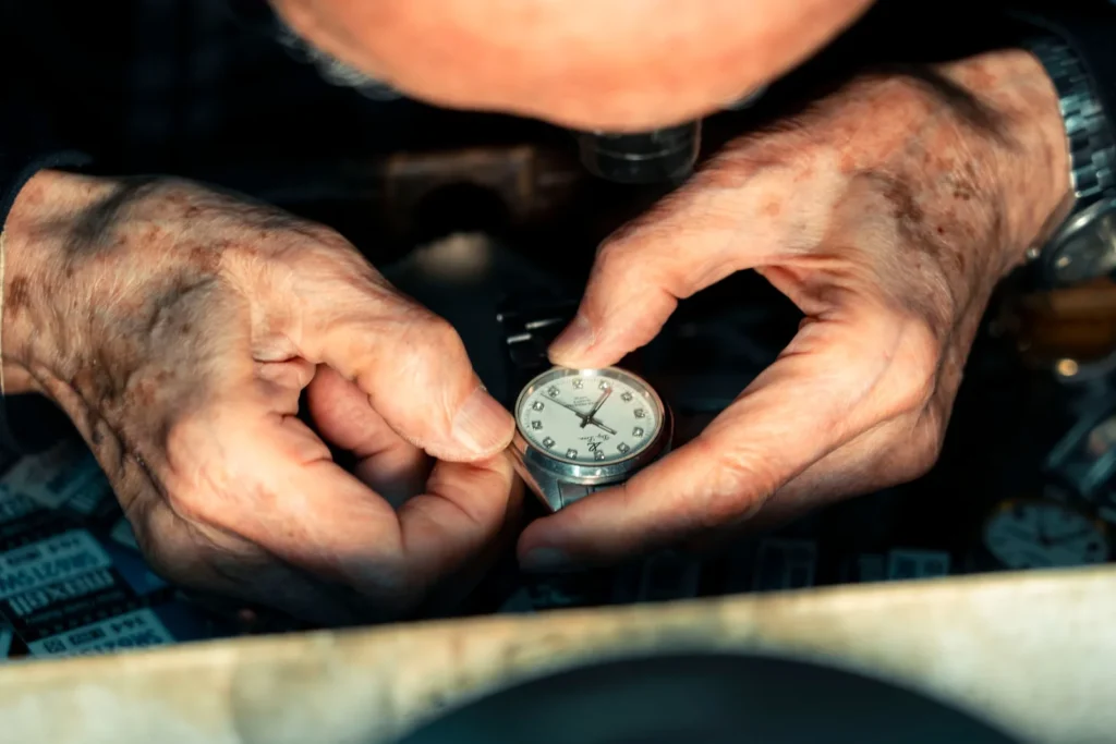 A watchmaker's hands holding a small movement