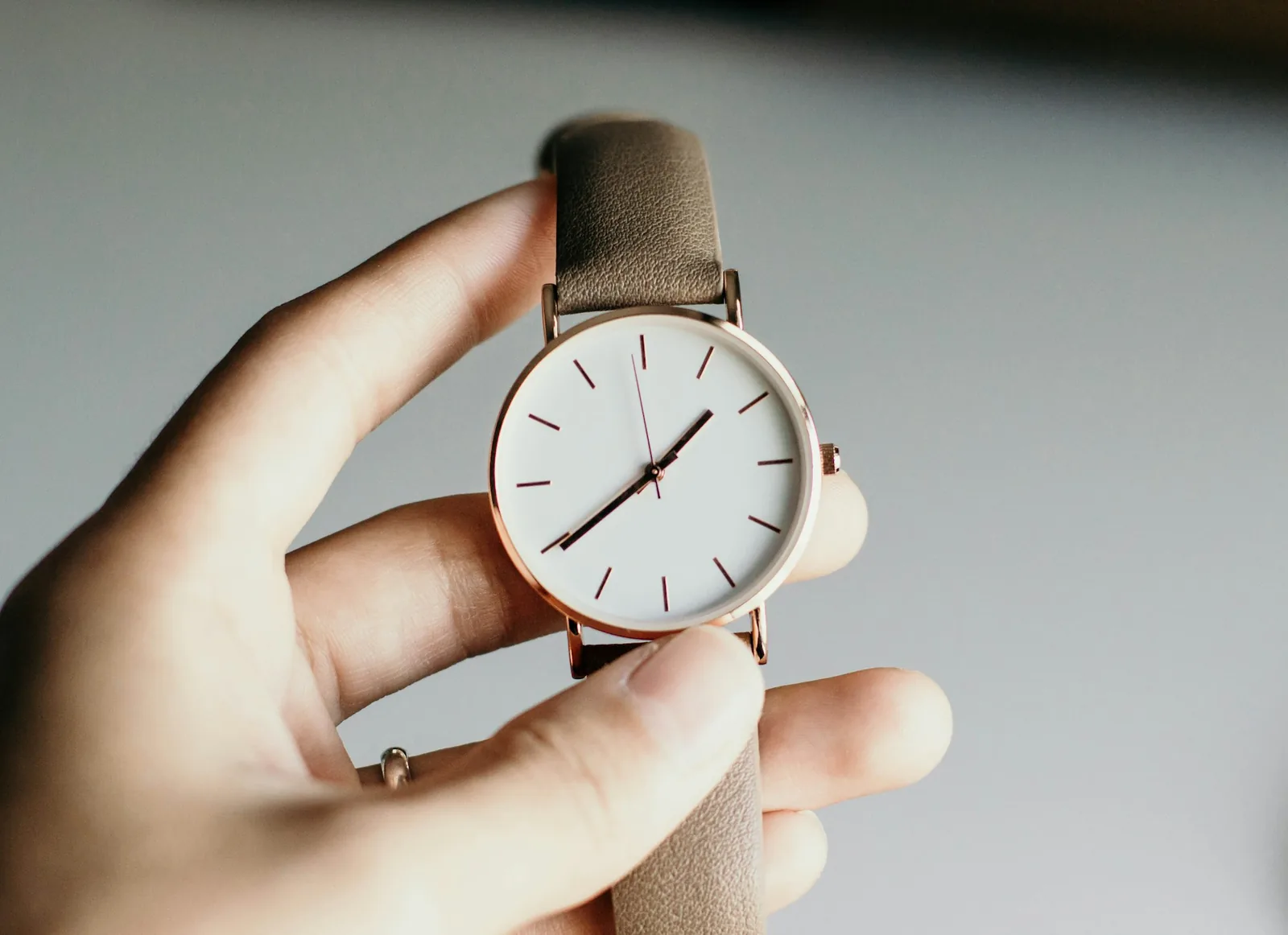 A slim dress watch on a leather strap emerging from a shirt cuff