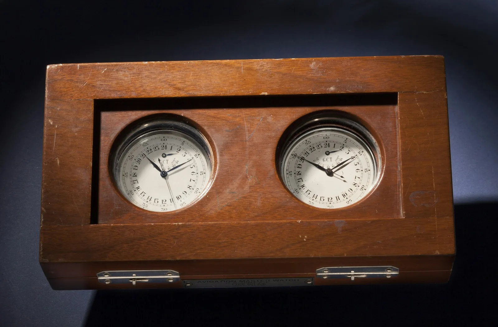 An antique marine chronometer mounted in a wooden case with a brass bezel