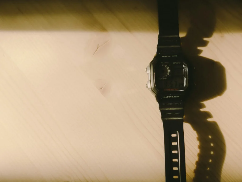 An older wristwatch with a patinated dial lying on a scratched wooden table