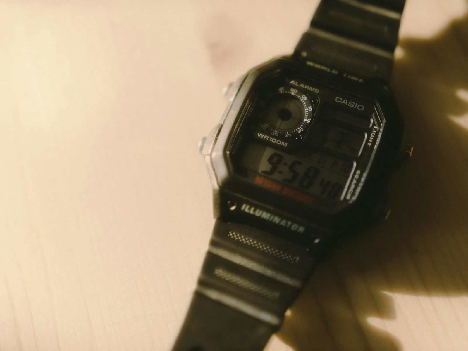 An older wristwatch with a patinated dial lying on a scratched wooden table