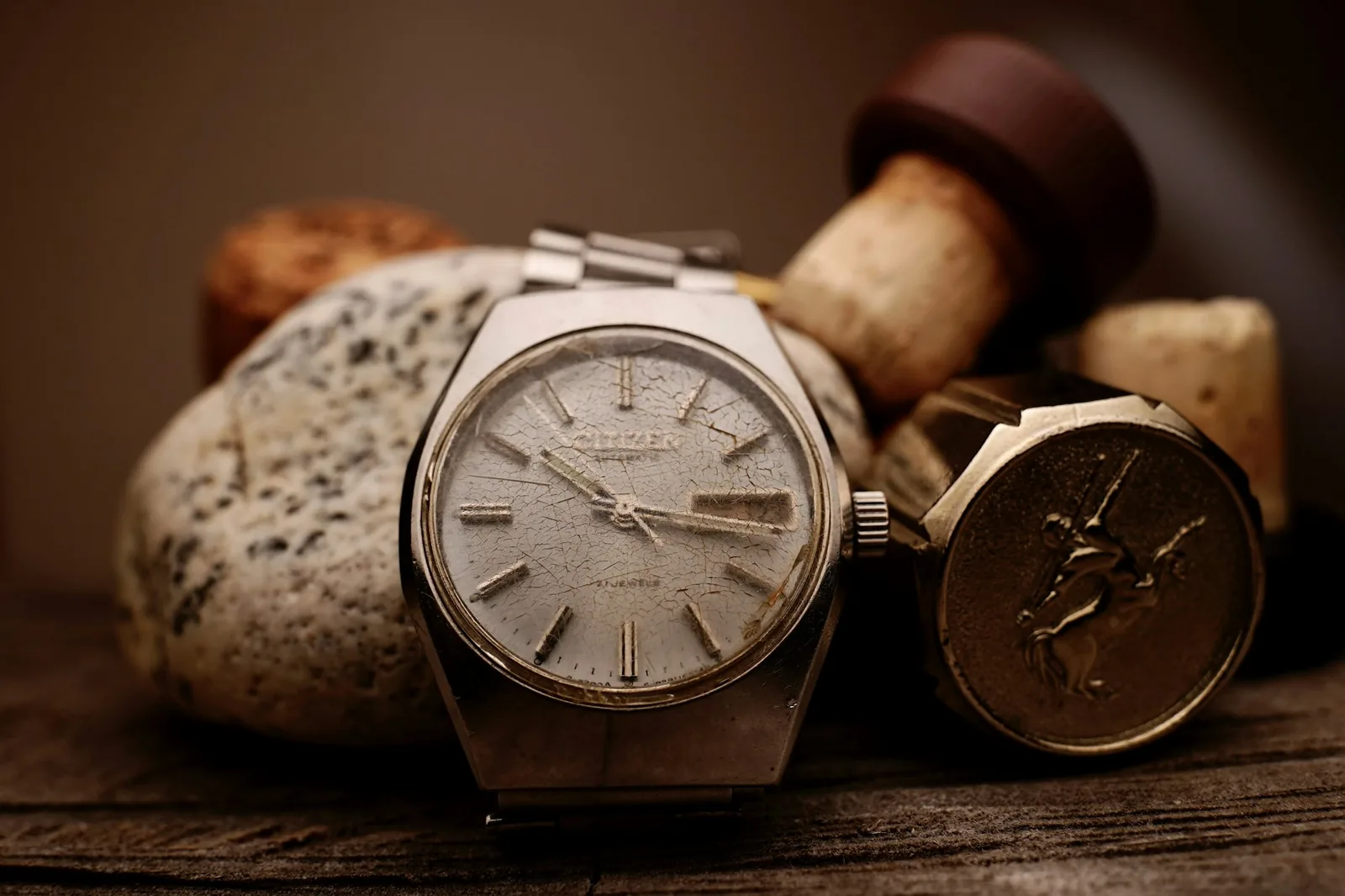 The aged dial of an old watch photographed close up, showing discoloured hour markers