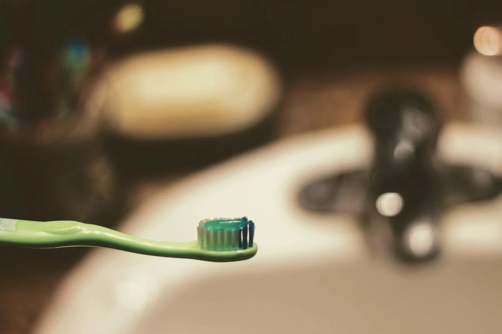 A soft toothbrush being used on the links of a steel watch bracelet over a sink