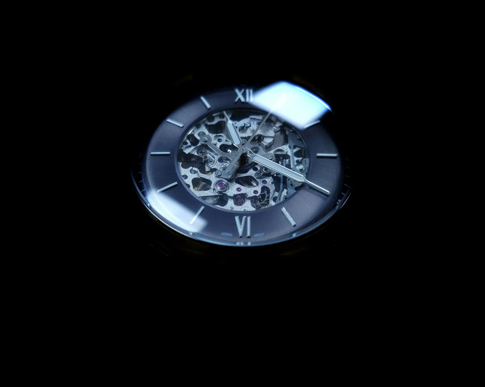 A watch dial glowing green in darkness, with the hour markers and hands illuminated