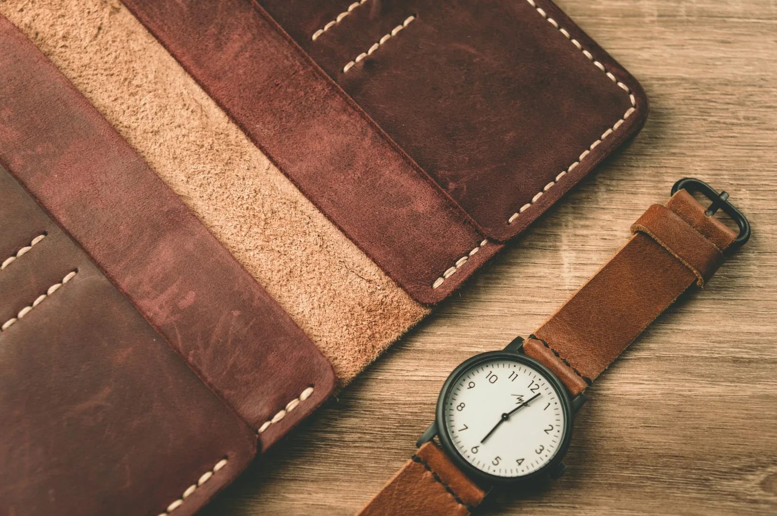 A brown leather watch strap laid flat with its buckle open