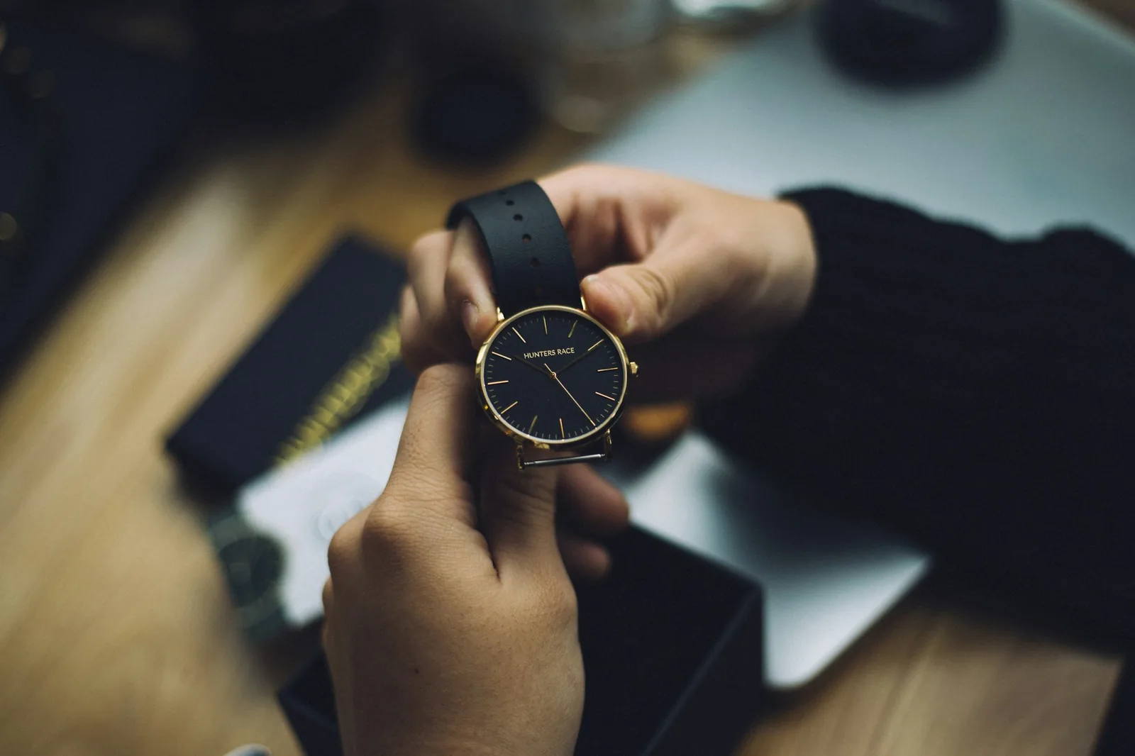 A person examining a wristwatch held between finger and thumb