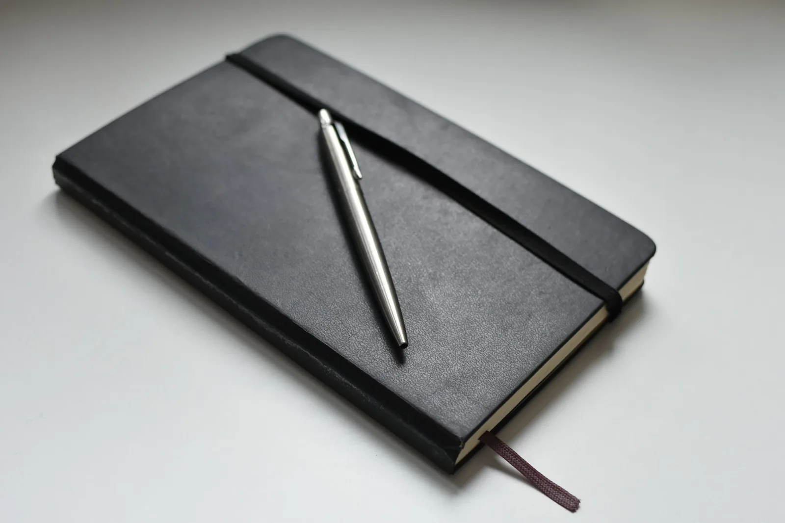 An open notebook and pen beside two wristwatches on a desk