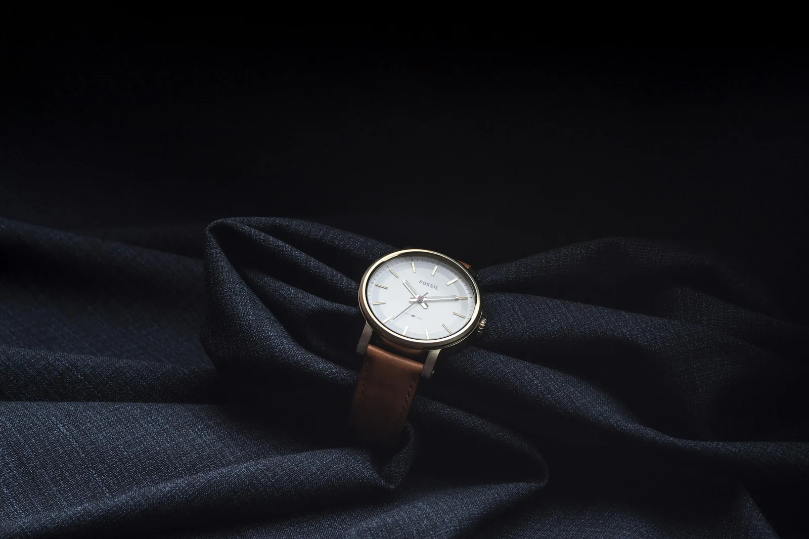 A wristwatch resting on folded cloth in soft light
