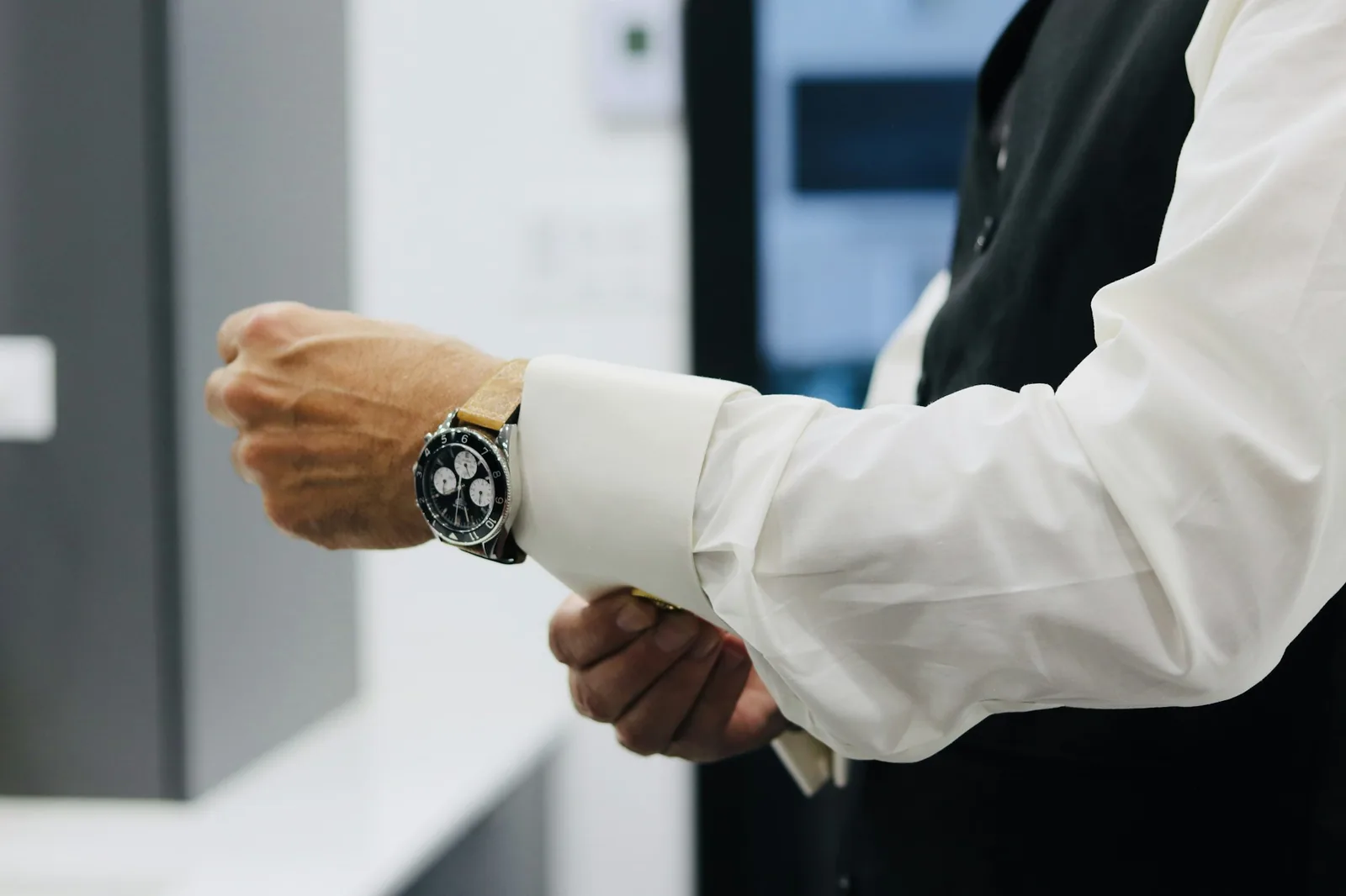 A watch case meeting the edge of a shirt cuff