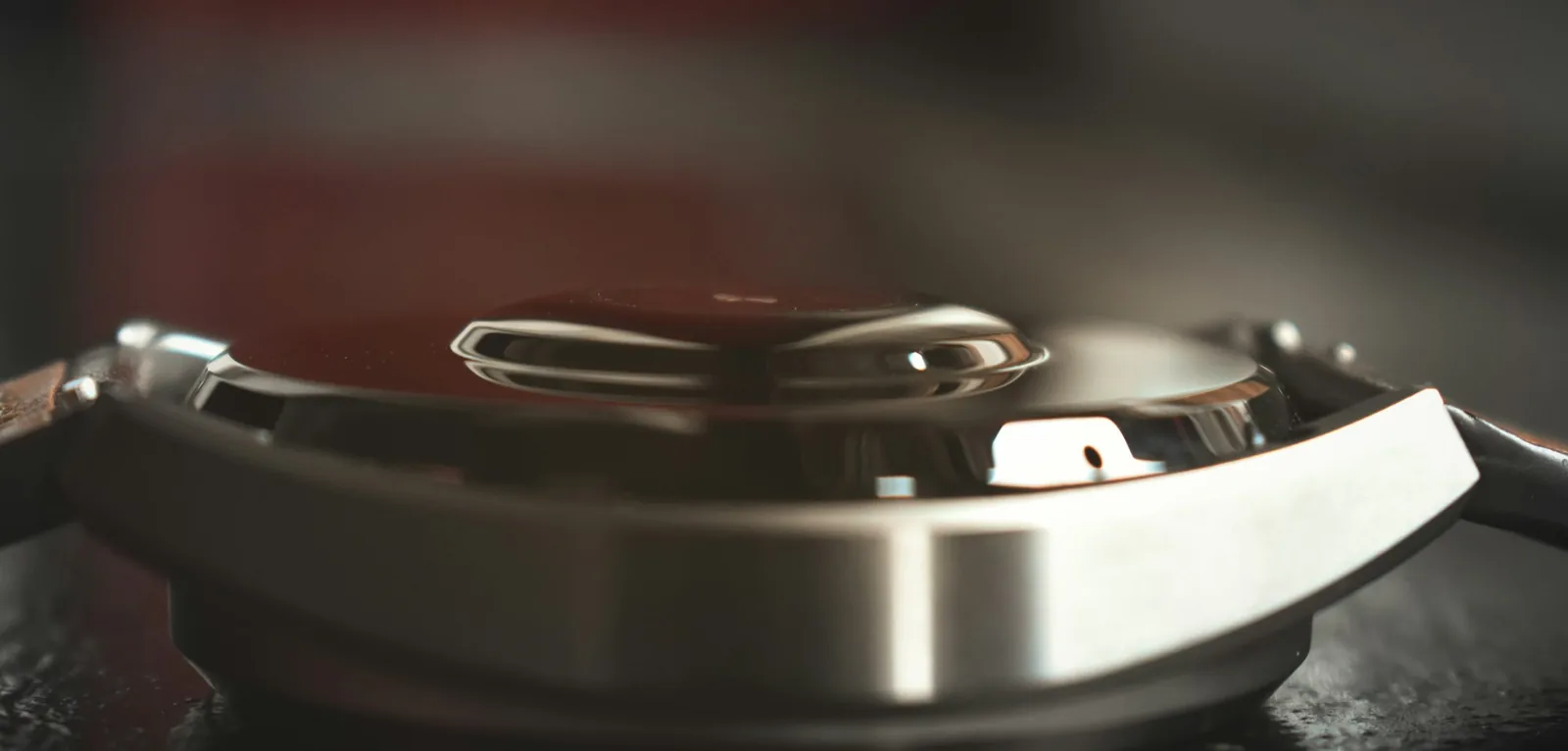 The brushed steel surface of a watch case photographed close up, showing the grain