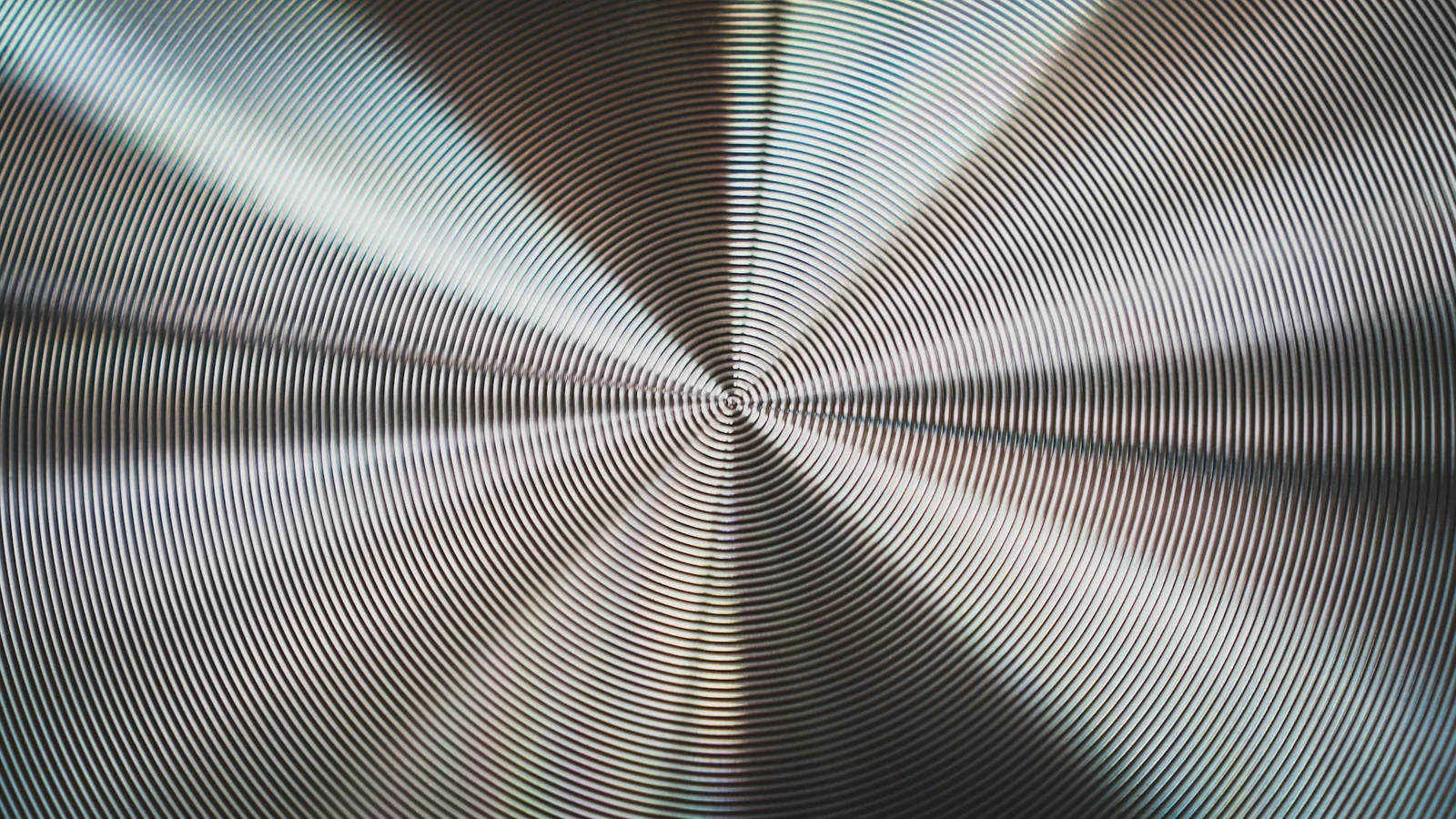 A brushed metal surface photographed close up, showing the direction of the grain