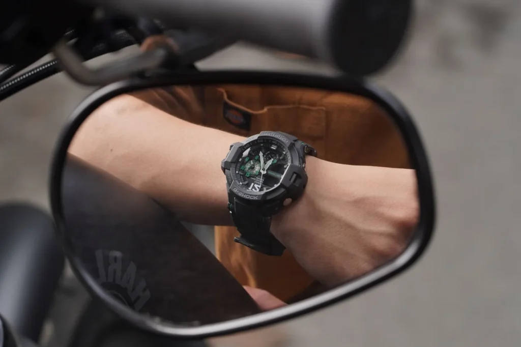 Two wristwatches with different dials lying side by side on a dark slate surface