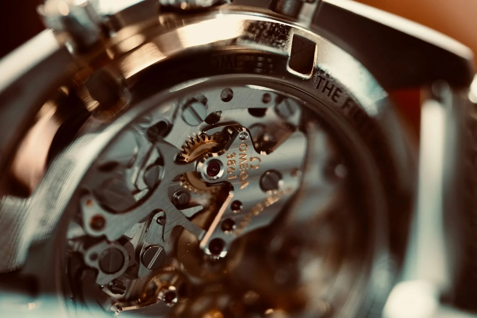 A macro photograph of an exposed watch movement showing the balance wheel and bridges