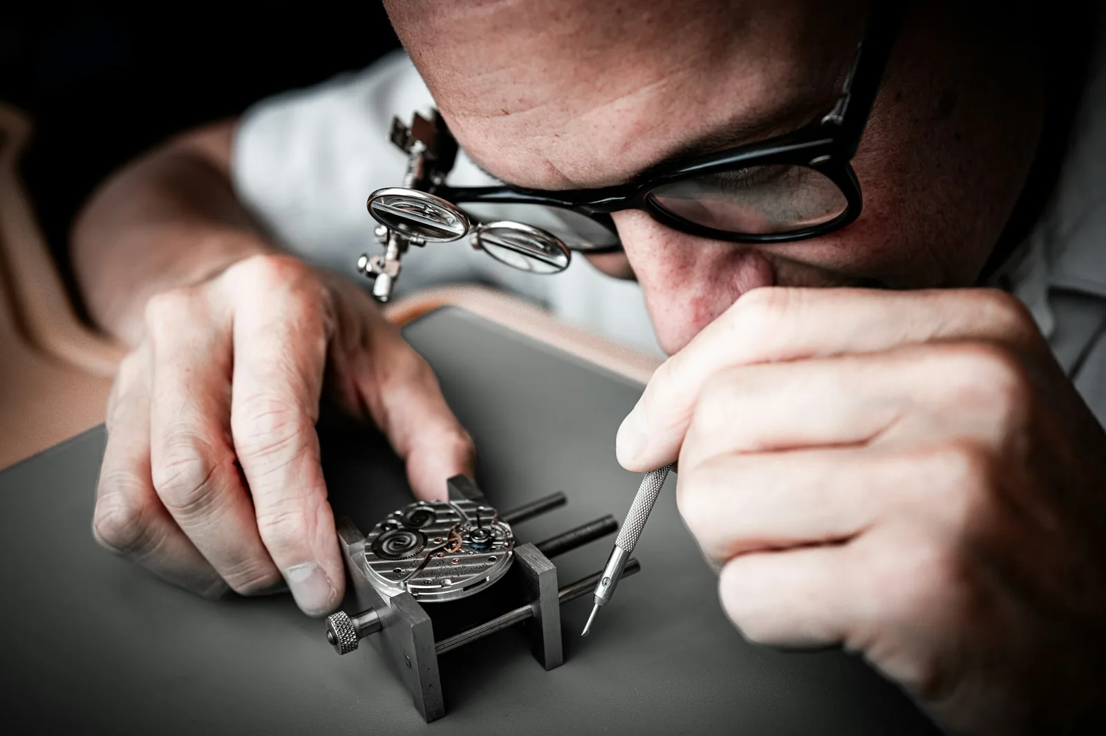 A watchmaker's bench with tools, an eyeglass and a partly disassembled movement