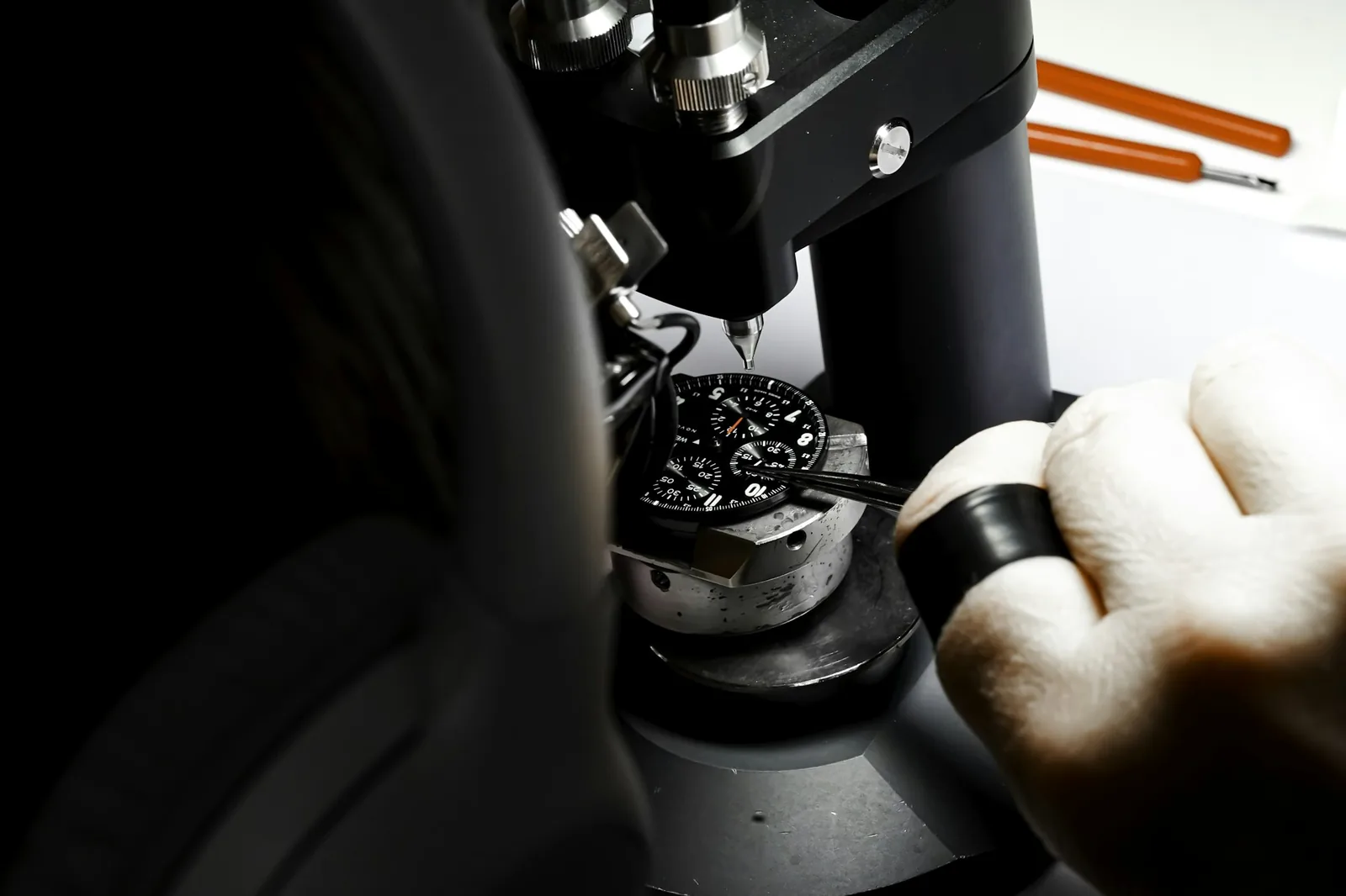 A watch being lowered into a pressure testing device in a workshop