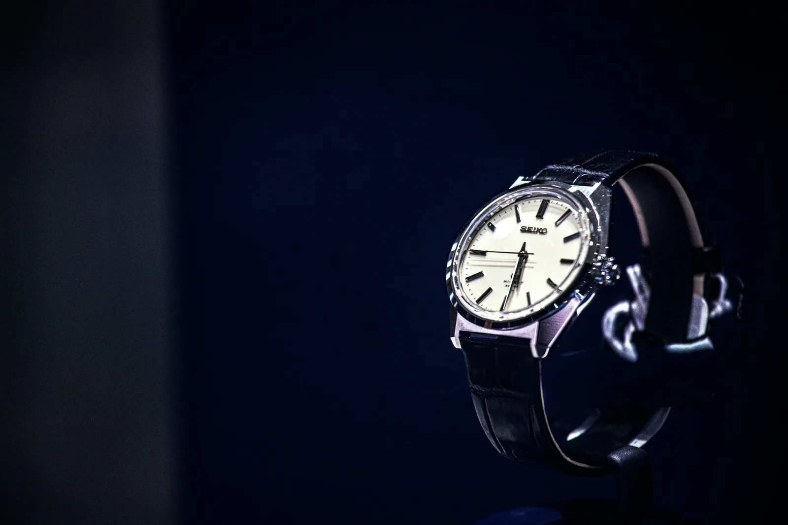A small vintage wristwatch with a round case photographed against a dark background