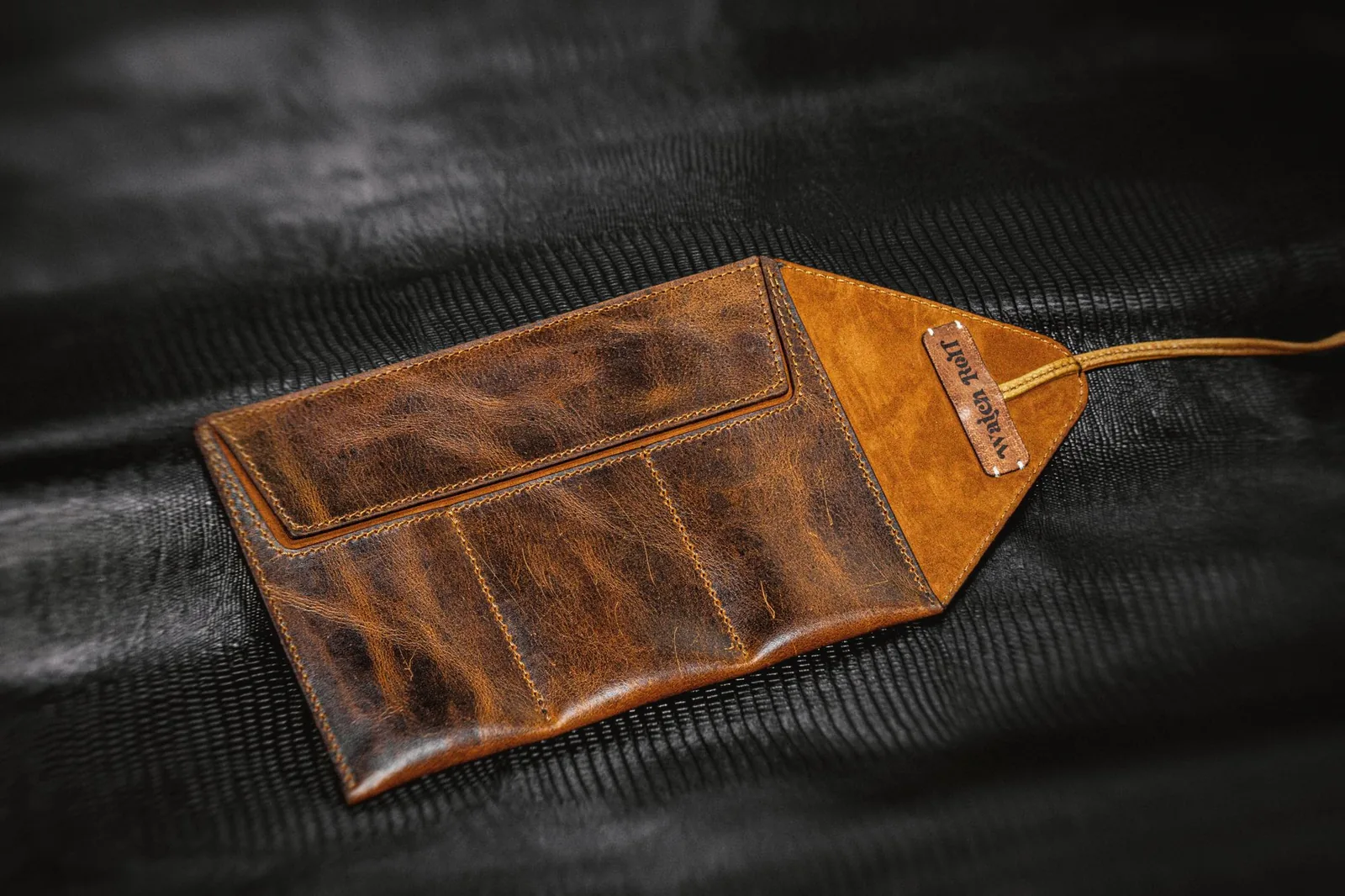 A rolled leather watch case open on a table with a wristwatch inside