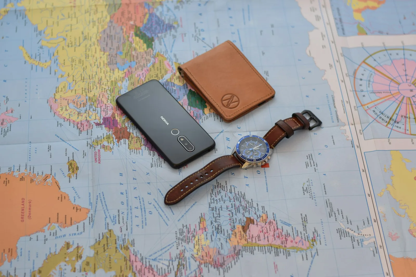 A wristwatch lying on a table beside a passport and boarding documents