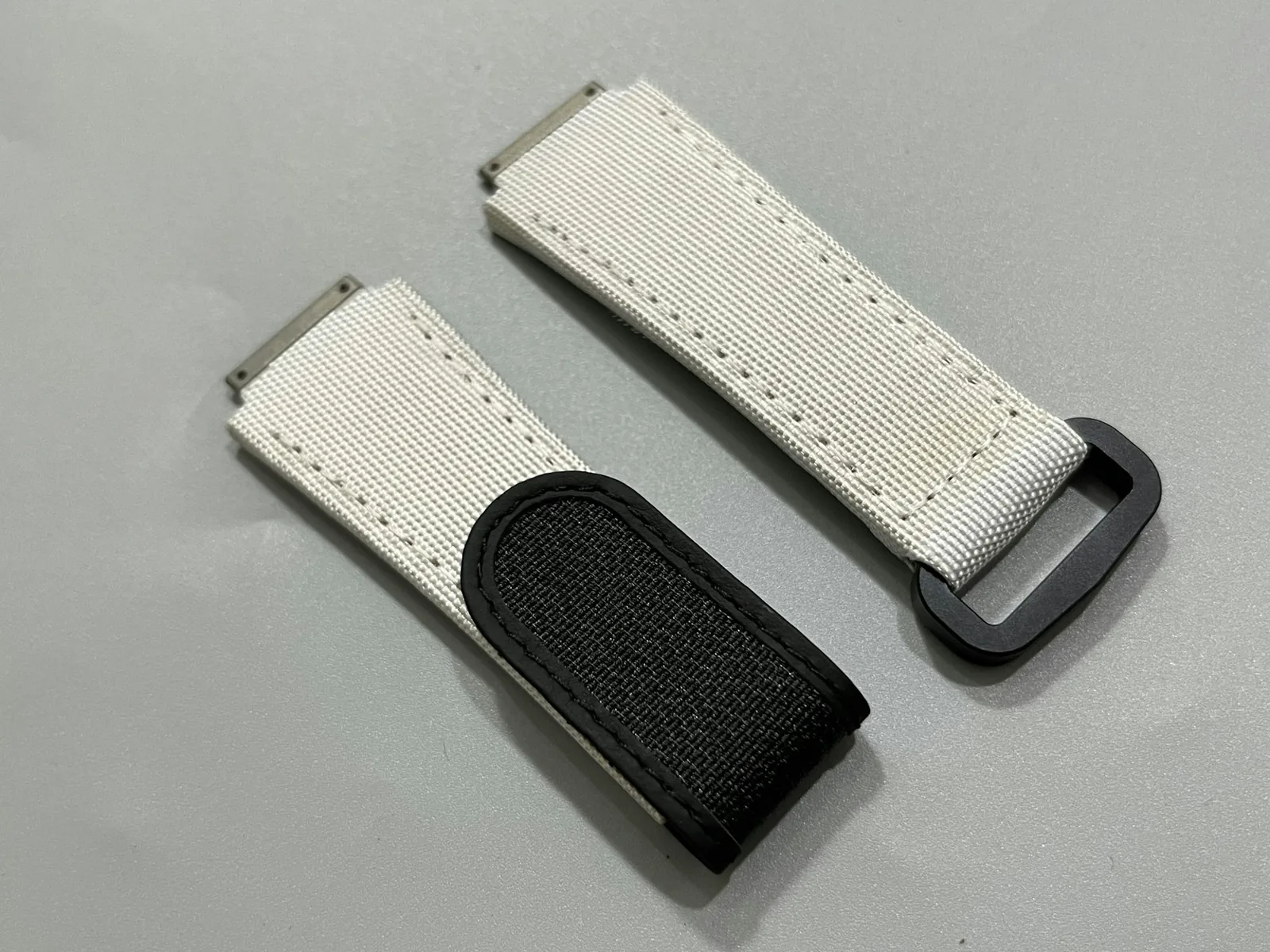 Several watch straps in leather, nylon and rubber laid out side by side on a plain surface