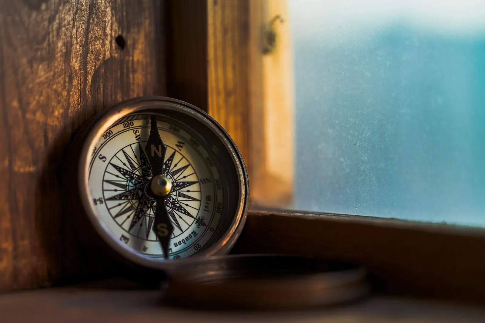 A small compass on a wooden surface with its needle deflected towards a metal object