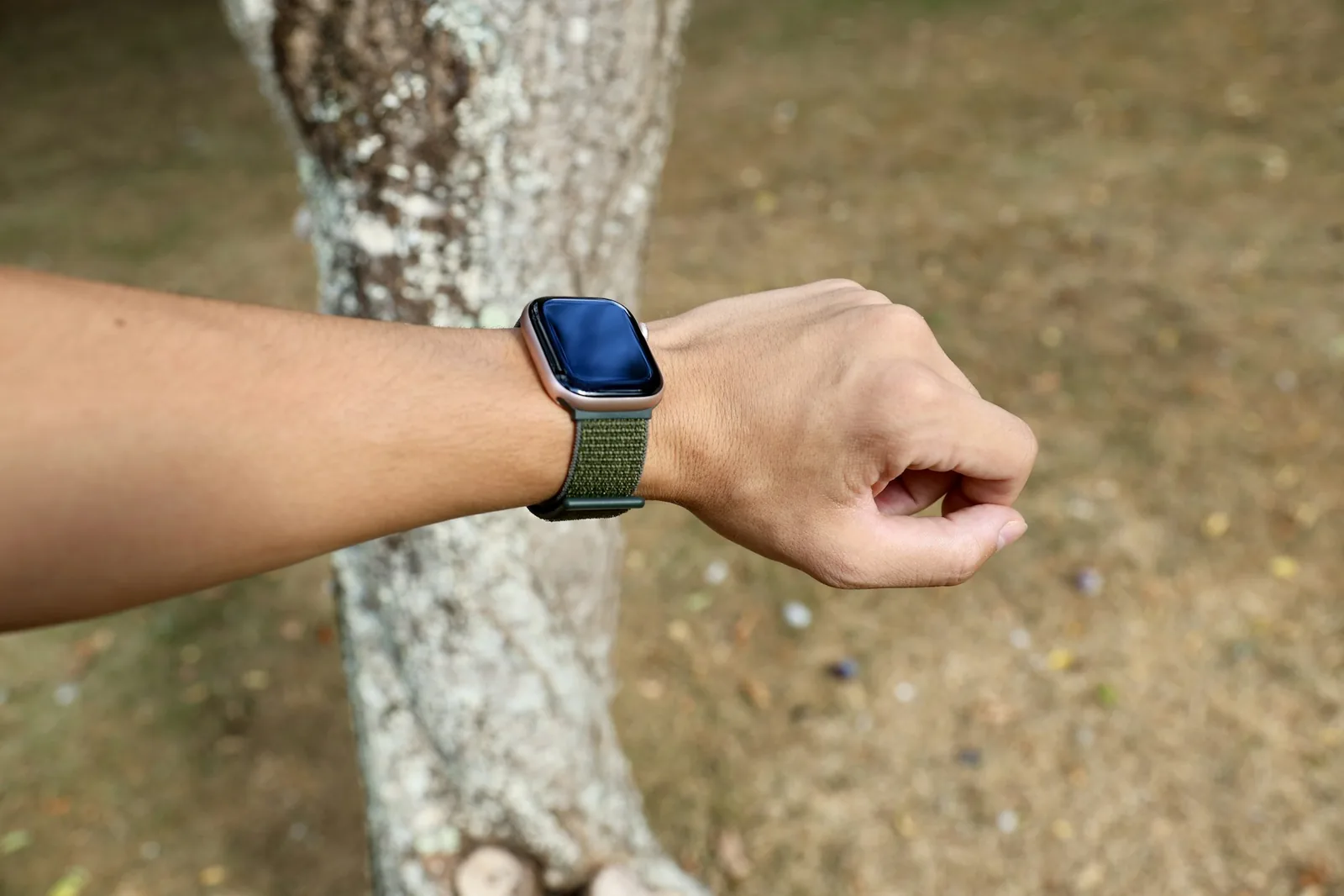 A robust wristwatch worn on a wrist outdoors against a blurred landscape