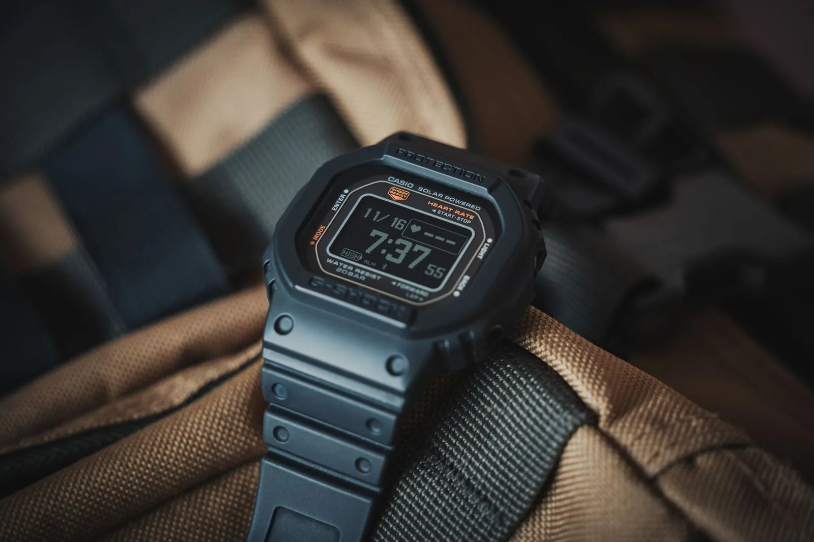 A rugged wristwatch resting on the strap of a hiking backpack